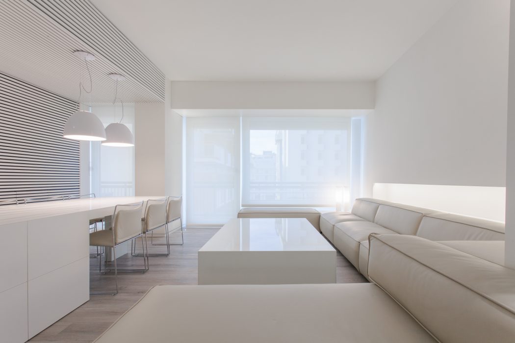 Minimalist living room with clean lines, white furniture, and large windows providing ample natural light.