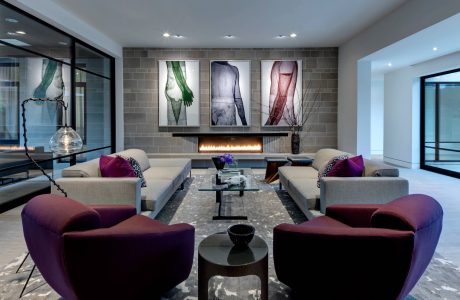 Sleek, modern living room with plush gray sofas, abstract artwork, and a cozy fireplace.