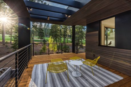 Stylish modern deck with wooden floor, metallic chairs, and scenic forest view.