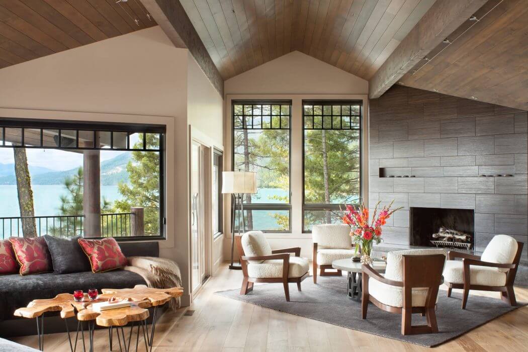 Cozy cabin-style living room with vaulted wooden ceiling, stone fireplace, and scenic mountain views.