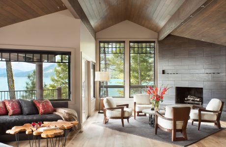 Cozy cabin-style living room with vaulted wooden ceiling, stone fireplace, and scenic mountain views.