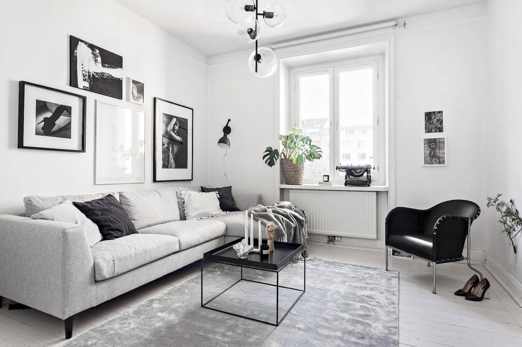 Minimalist living room with gray sofa, black accent chair, and framed black and white artwork.