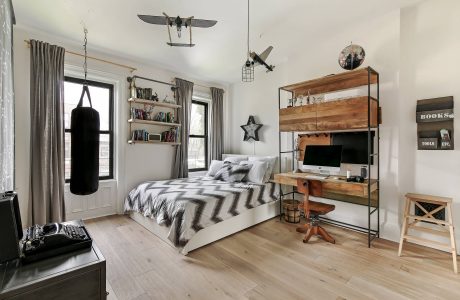 Rustic, industrial-style bedroom with wooden shelving, metal accents, and suspended model planes.