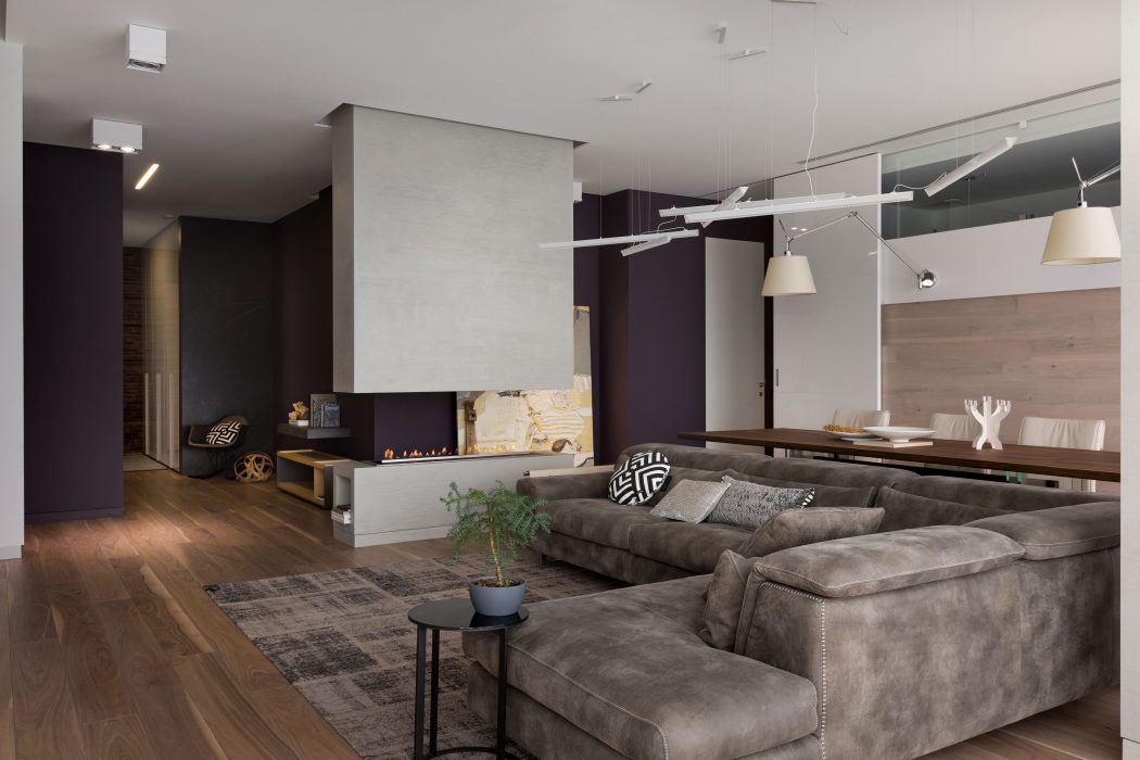 Sleek, modern living space with minimalist furnishings, warm wood flooring, and recessed lighting.