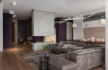 Sleek, modern living space with minimalist furnishings, warm wood flooring, and recessed lighting.