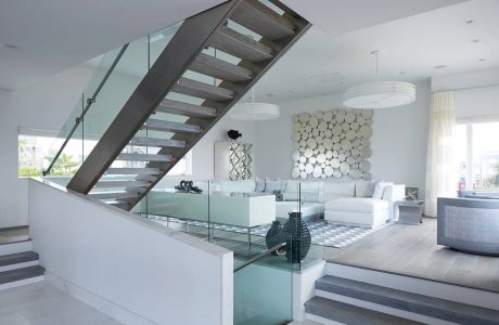 Striking modern staircase and sleek interior design with glass accents and abstract art.