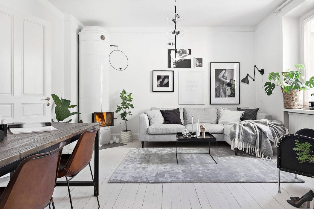 Cozy Scandinavian-style living room with wooden accents, gallery wall, and lush greenery.