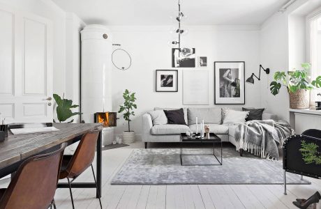 Cozy Scandinavian-style living room with wooden accents, gallery wall, and lush greenery.