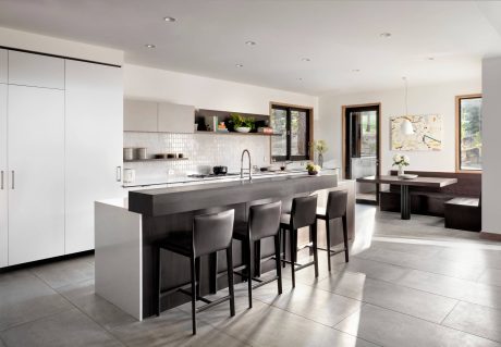 Sleek, modern kitchen with minimalist white cabinetry, concrete countertops, and bar seating.