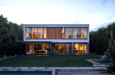 Modern two-story house with glass walls, wooden accents, and a swimming pool.