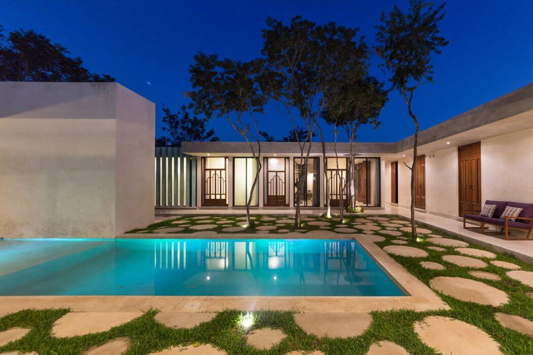Elegant modern home with a tranquil pool, lush landscaping, and charming architectural details.