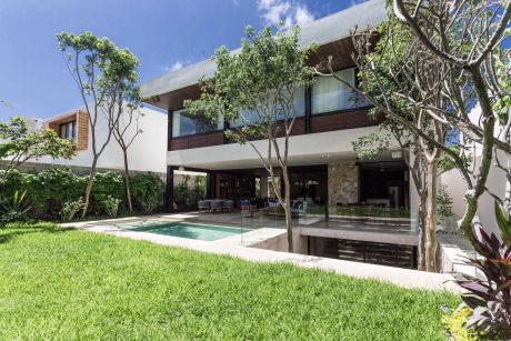 Sleek, modern architecture with glass walls, lush greenery, and a tranquil pool.