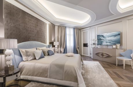 Luxurious bedroom with intricate ceiling molding, plush bedding, and modern furnishings.