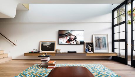 Minimalist living room with wooden media console, framed artwork, and patterned area rug.