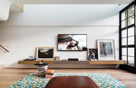 Minimalist living room with wooden media console, framed artwork, and patterned area rug.