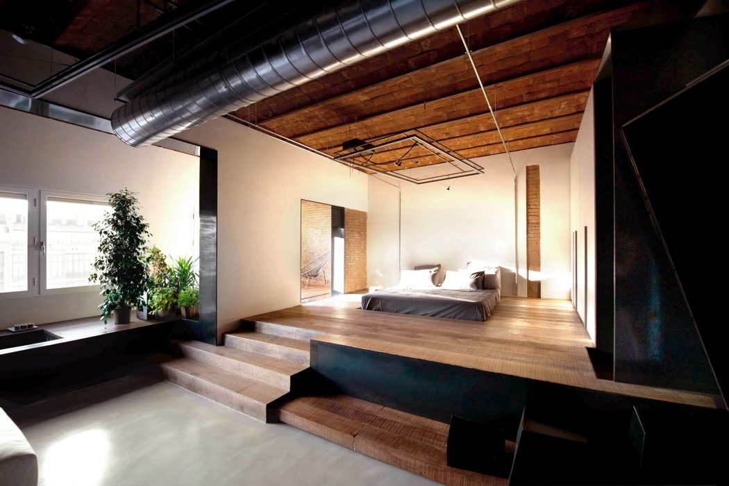 Sleek, modern interior with wood beams, raised platform, and lush indoor plants.