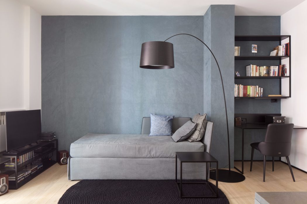 Minimal, modern living room with sleek furniture, a floor lamp, and built-in shelving.