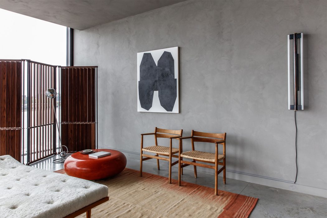 Minimalist interior with concrete walls, wooden furniture, and abstract artwork.
