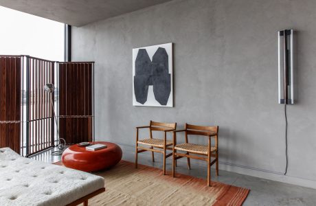 Minimalist interior with concrete walls, wooden furniture, and abstract artwork.