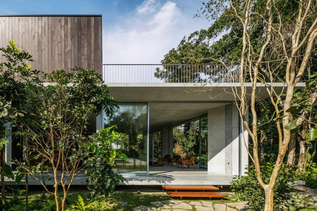 A modern, open-concept home surrounded by lush greenery and wooden accents.