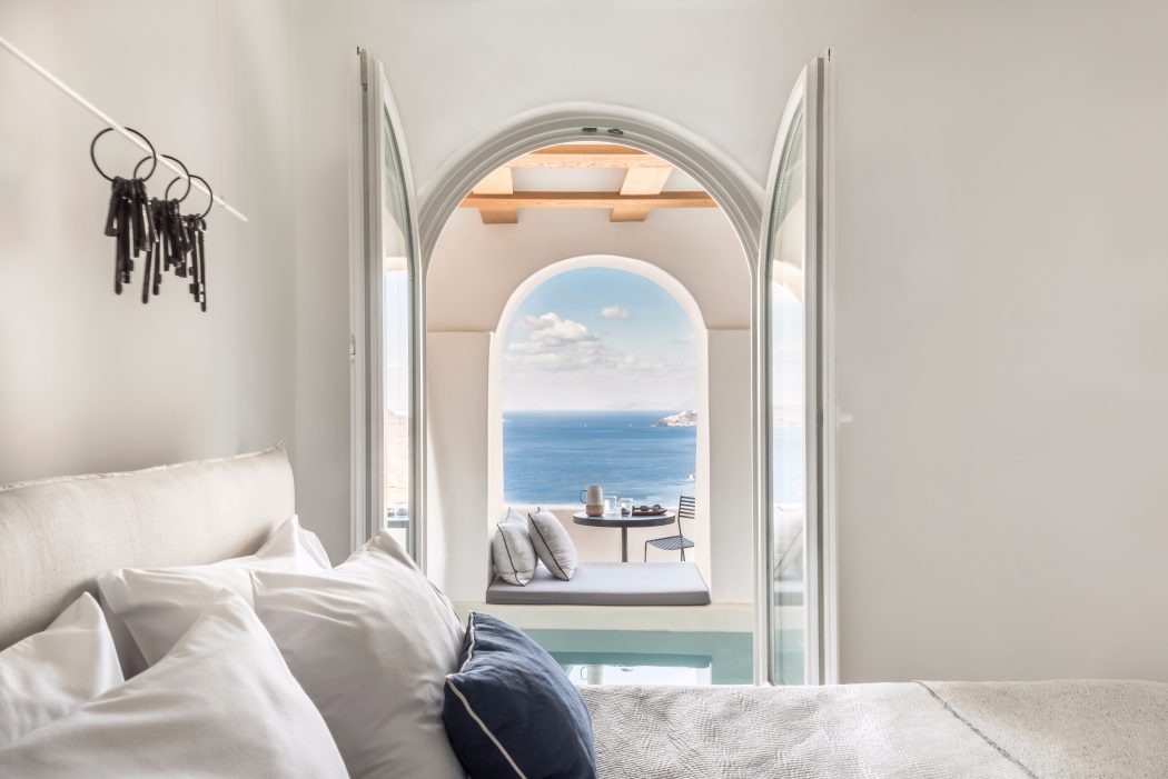 Serene bedroom with arched window frame overlooking tranquil sea view and horizon.