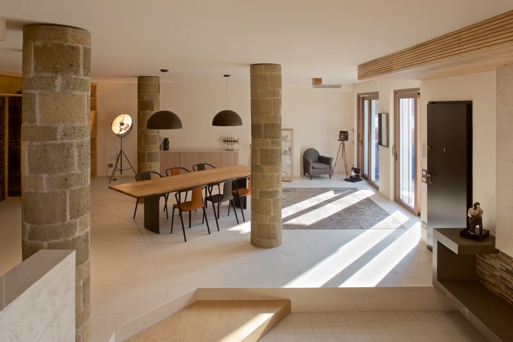 Spacious open-concept living area with stone columns, wood furniture, and modern lighting.