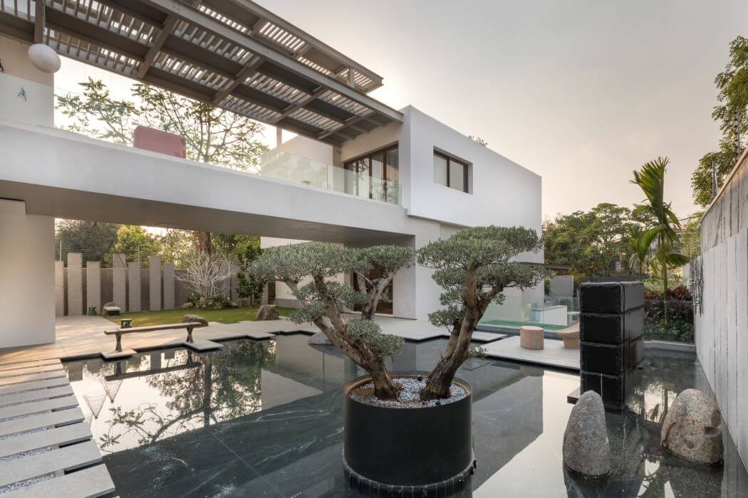 A modern, minimalist architectural design with a tranquil water feature and potted bonsai.