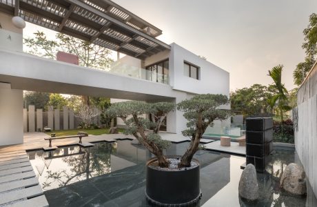 A modern, minimalist architectural design with a tranquil water feature and potted bonsai.