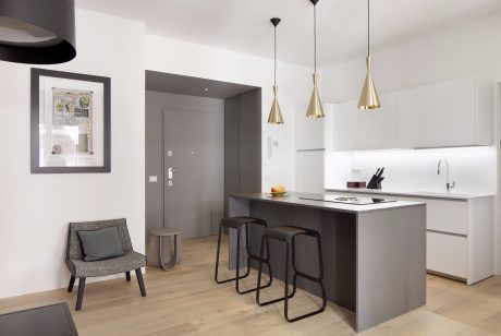 Well-designed modern kitchen with sleek gray cabinets, minimalist pendants, and a wooden breakfast bar.