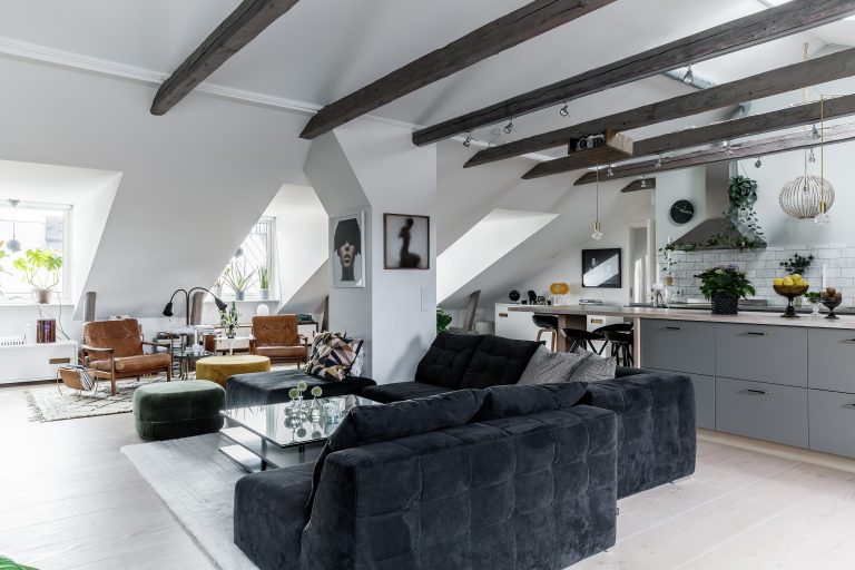 Eclectic loft-style interior featuring exposed beams, minimalist kitchen, and cozy living area.