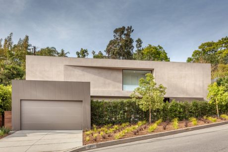 Modern single-story home with clean lines, large windows, and lush landscaping.