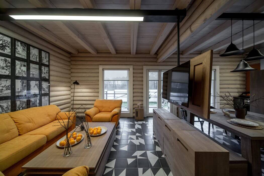 Rustic log cabin interior with modern furnishings, geometric patterned floor tiles, and pendant lighting.