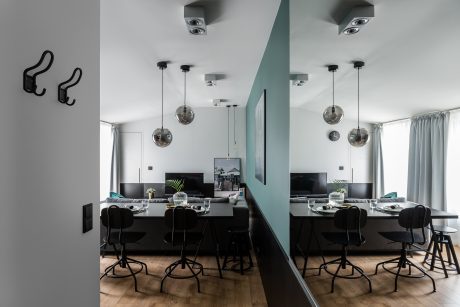 A modern dining room with sleek black furniture, pendant lights, and a minimalist design.