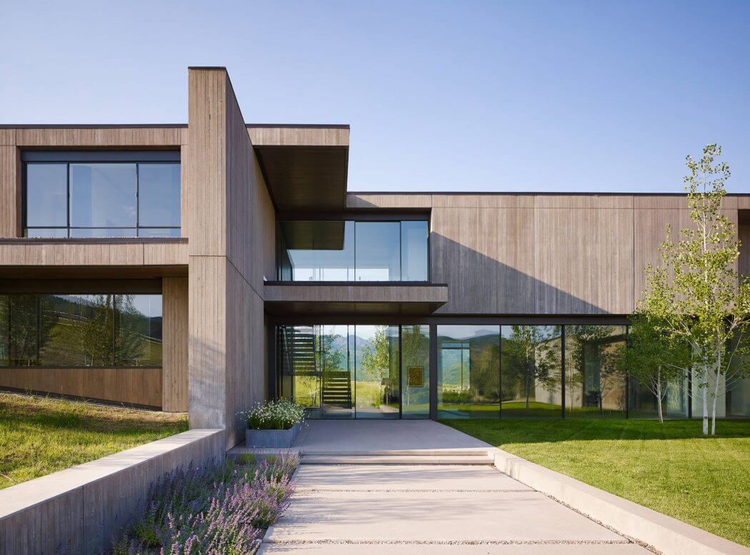 Striking modern architecture with clean lines, expansive glass walls, and lush landscaping.