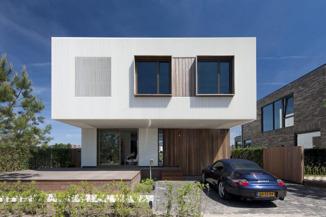 Modern two-story house with clean white facade, wooden accents, and large windows.