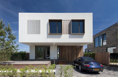 Modern two-story house with clean white facade, wooden accents, and large windows.