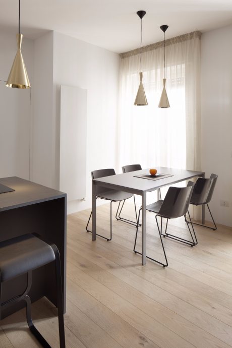 Minimalist dining room with modern pendant lighting, sleek furniture, and warm wood flooring.