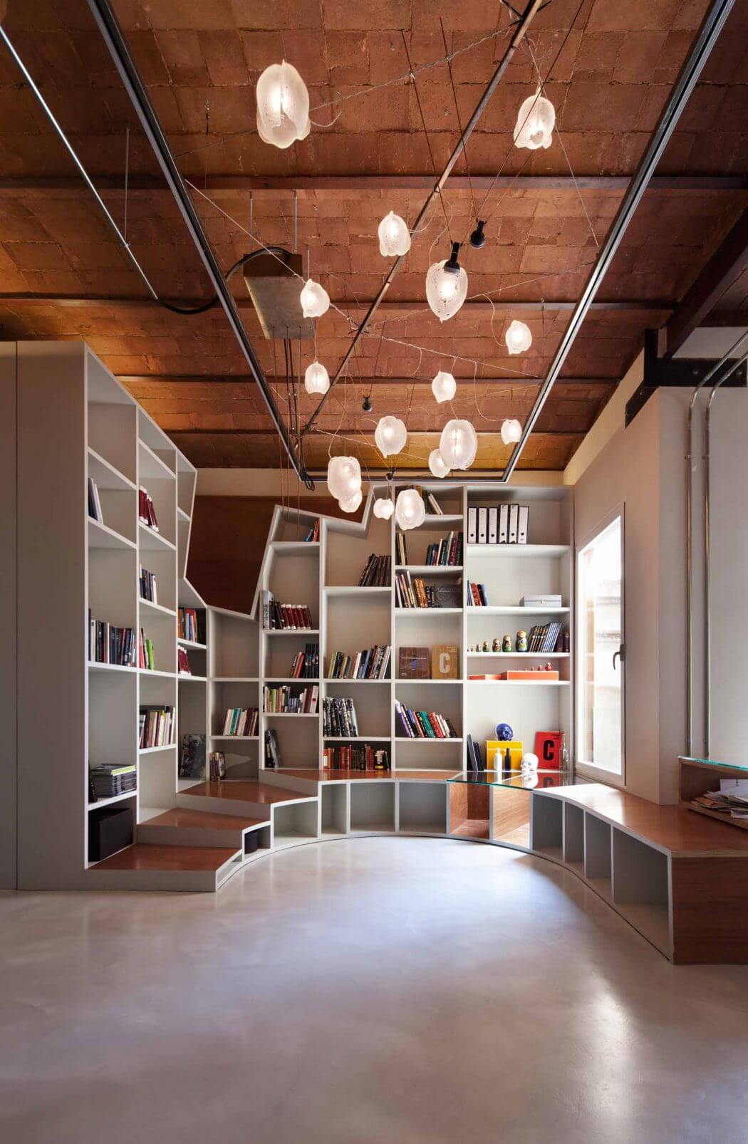 A cozy library space with intricate wooden ceiling, built-in bookshelves, and modern lighting.