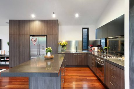 Modern kitchen with sleek, dark-toned cabinetry, stainless steel appliances, and wood floors.