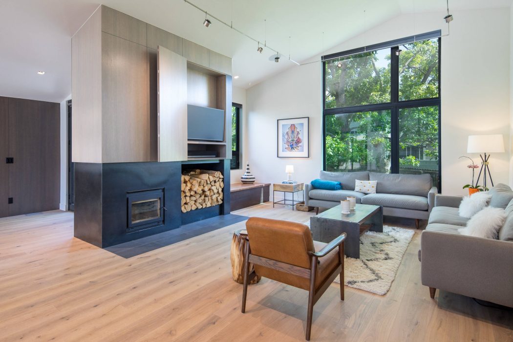 Spacious living room with modern fireplace, wooden furniture, and large window offering garden views.