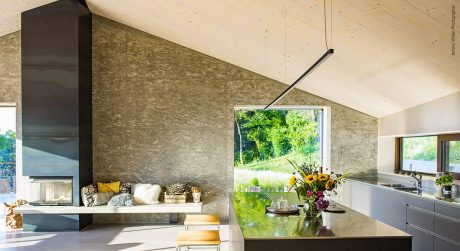 Spacious modern kitchen with large windows overlooking lush green landscape.