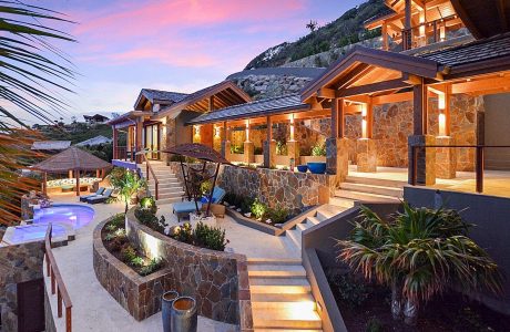 Stunning mountain retreat with rustic stone and wood architecture, lush landscaping.