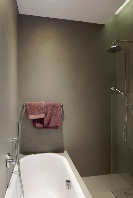 A modern bathroom with a minimalist design, featuring a freestanding bathtub and a rainfall shower.