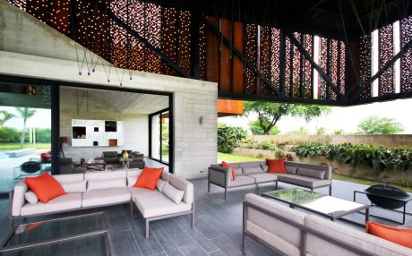 Sleek modern patio with cozy seating, lush greenery, and an intricate lighting fixture.