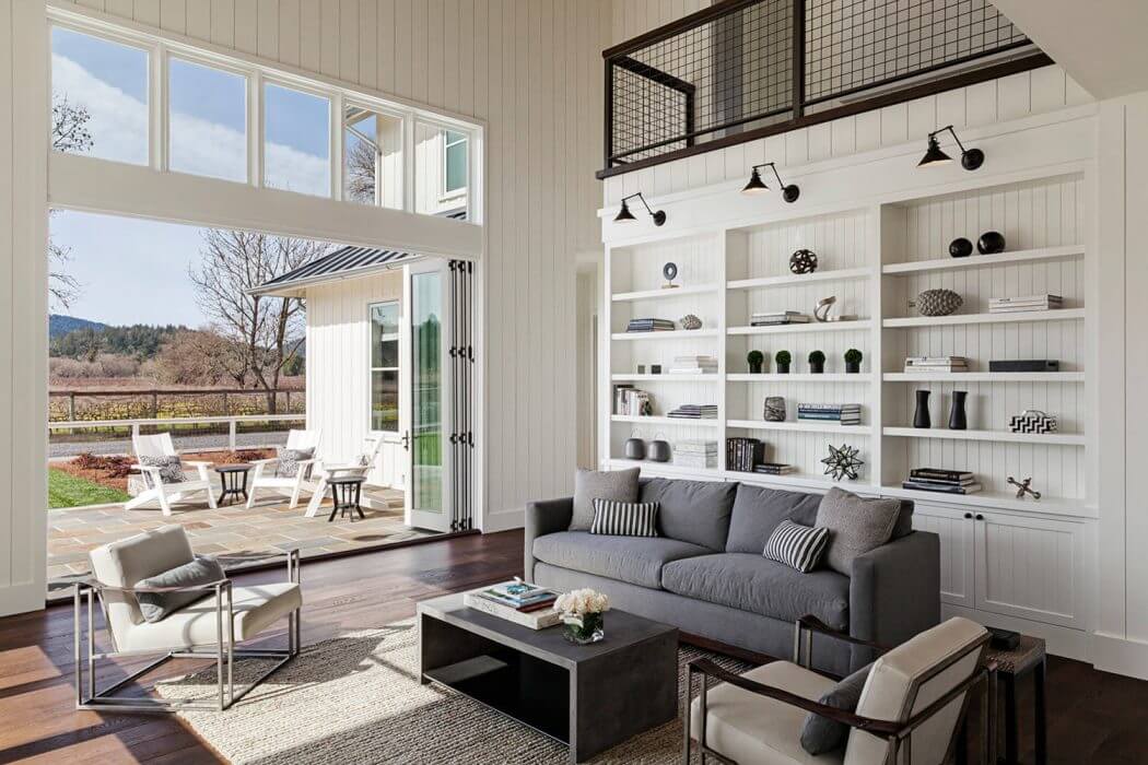 Spacious living room with large windows, white wall paneling, and built-in shelving.