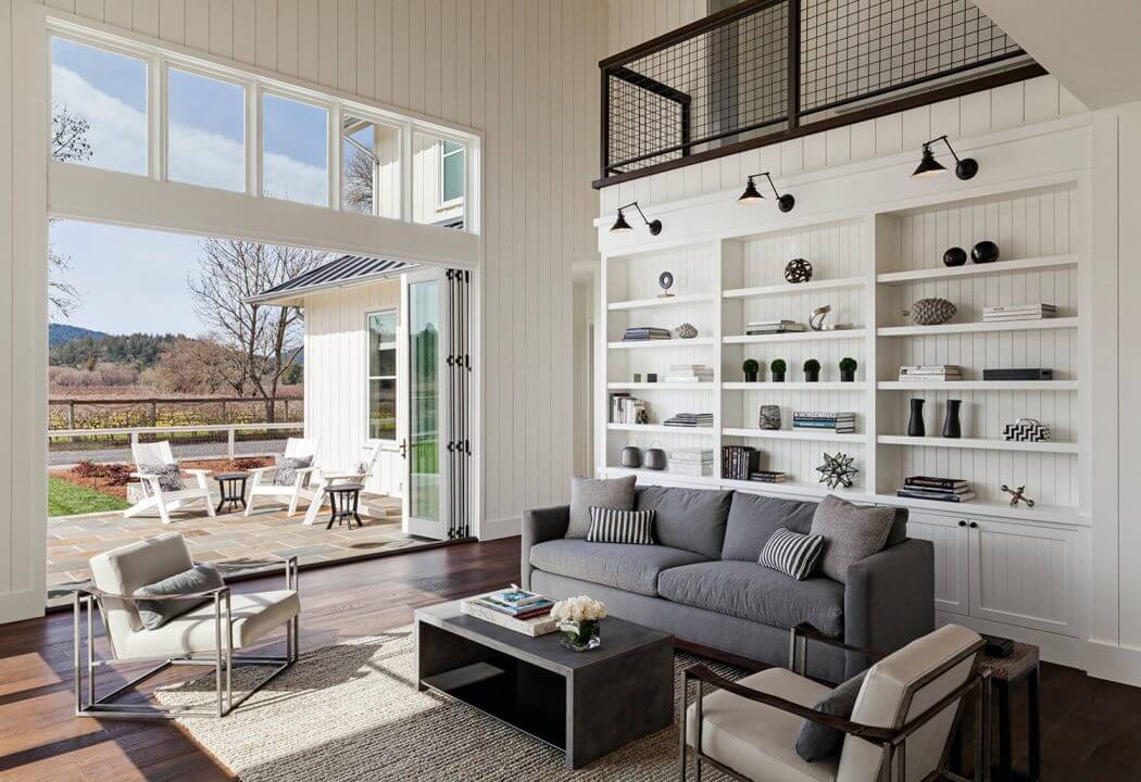 Spacious living room with large windows, white wall paneling, and built-in shelving.