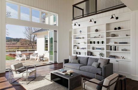 Spacious living room with large windows, white wall paneling, and built-in shelving.