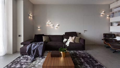 Minimalist living room with dark sofa, wooden coffee table, and modern wall sconces.