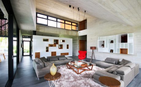 Spacious modern living room with concrete walls, high ceilings, and sleek furniture.