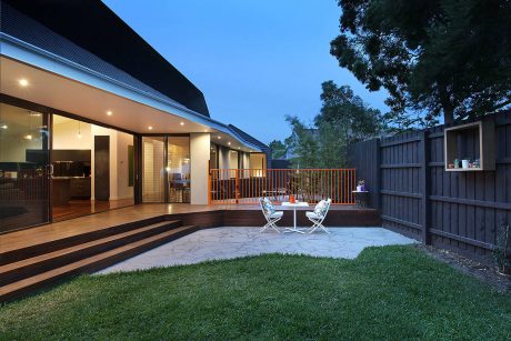Well-designed modern outdoor living space with wooden deck, seating, and lush greenery.